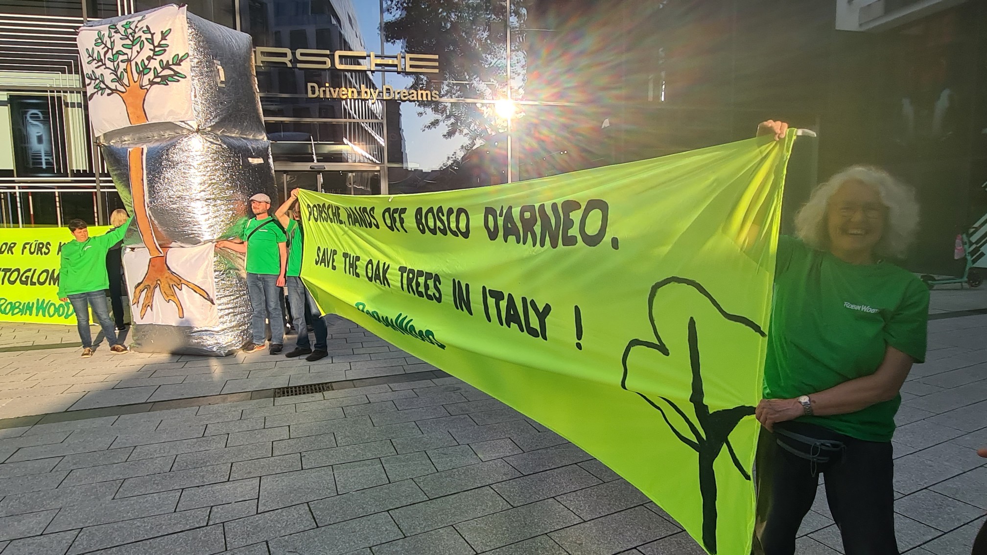 Aktivistin mit gelbem Protestbanner gegen drohende Waldzerstörung durch Porsche