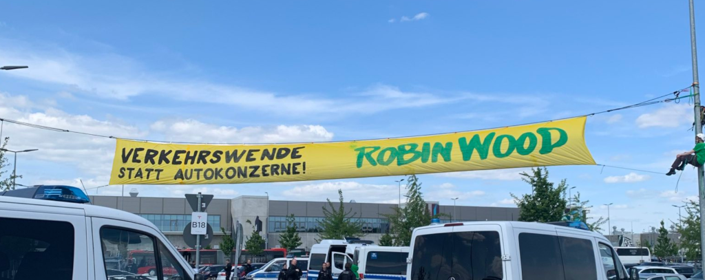 Protestbanner zwischen Laternen vor dem Tesla-Werk