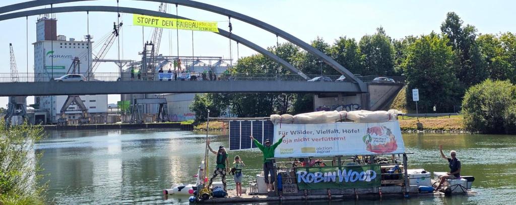 Floß vor Agraviswerk und Brück mit Protestbanner