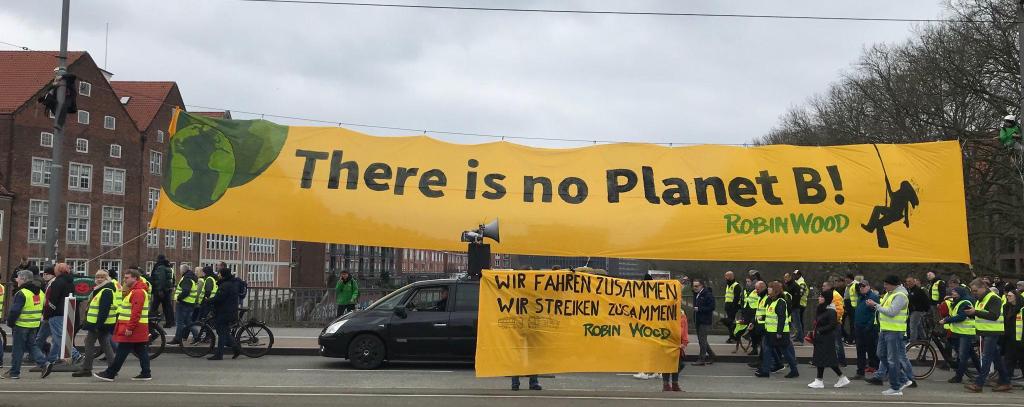 Demo auf einer Brücke unter gelbem Protestbanner