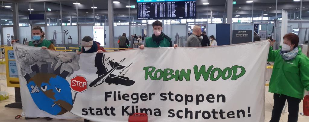 Banner mit der Aufschrift Flieger stoppen statt Klima schrotten in der Abflughalle im Flughafen Köln/Bonn