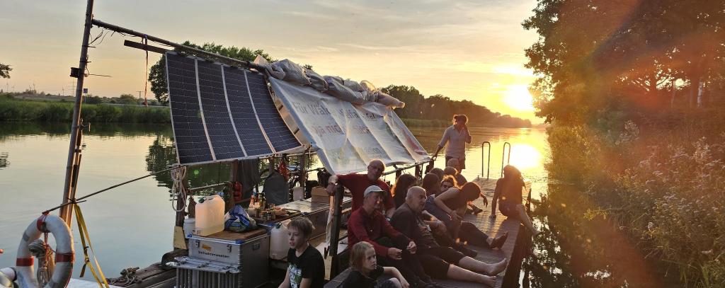 Floß mit Menschen bei Sonnenuntergang