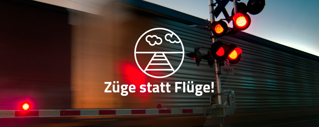 Das Bild zeigt einen Bahnübergang mit einer roten Ampel. Hinter der Ampel fährt ein Guterzug vorbei. Auf dem Bild ist das Kampagnenlogo und der Slogan "Züge statt Flüge" in weißer Schrift zu sehen.