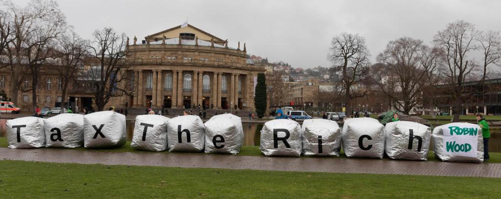 Aktivist*innen mit großen silbernen Würfeln vor der Stuttgarter Oper, Aufschrift: Tax The Rich